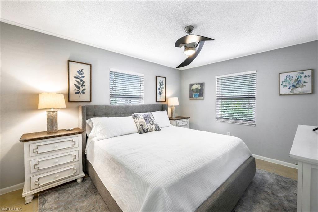 Bedroom featuring a textured ceiling, a ceiling fan, and light tile patterned flooring
