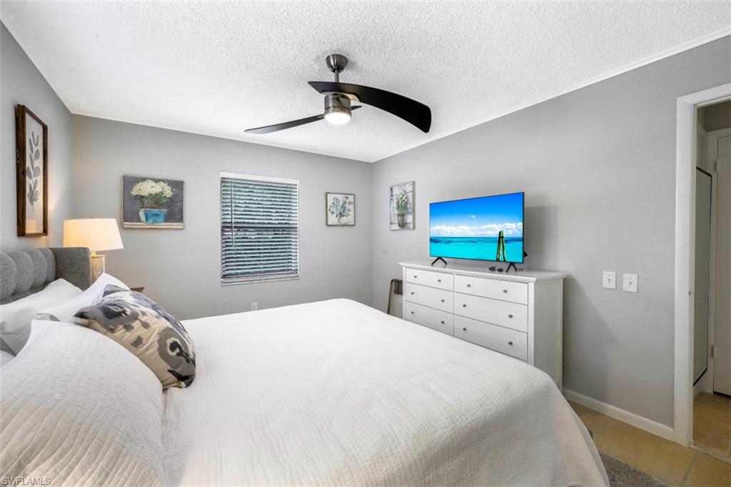 Bedroom with a textured ceiling, ceiling fan, and light tile patterned floors