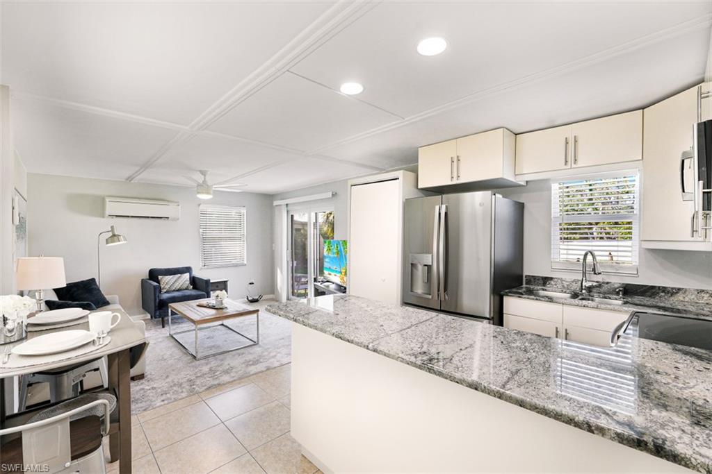 Kitchen featuring stainless steel refrigerator with ice dispenser, light stone counters, light tile patterned floors, a peninsula, and recessed lighting