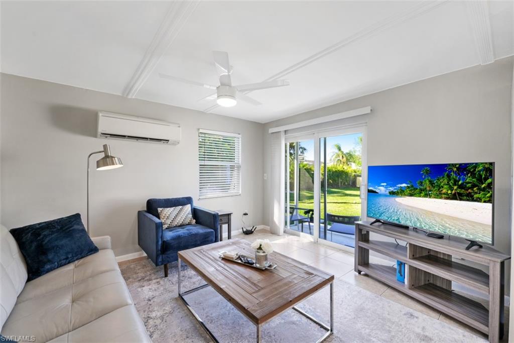 Tiled living room with ceiling fan and a wall mounted air conditioner