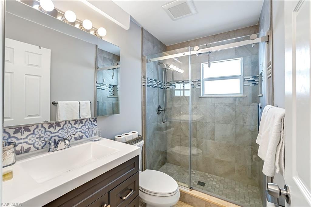Bathroom with vanity, a shower stall, and backsplash