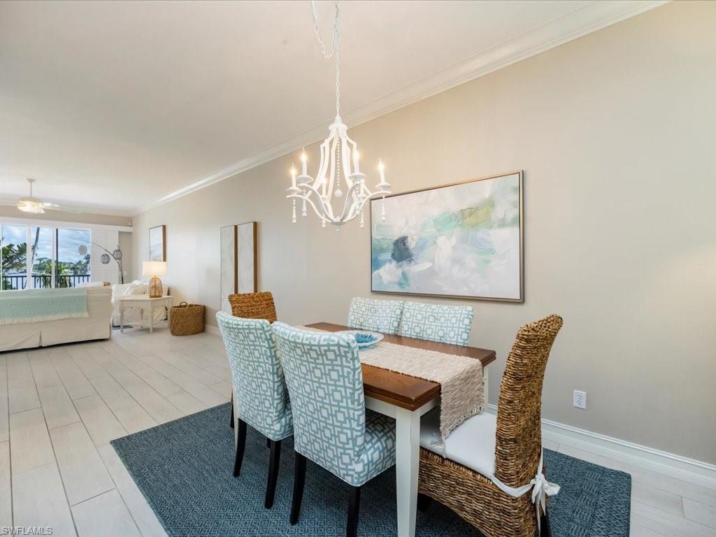 Dining area featuring crown molding, light wood-style floors, a chandelier, and ceiling fan