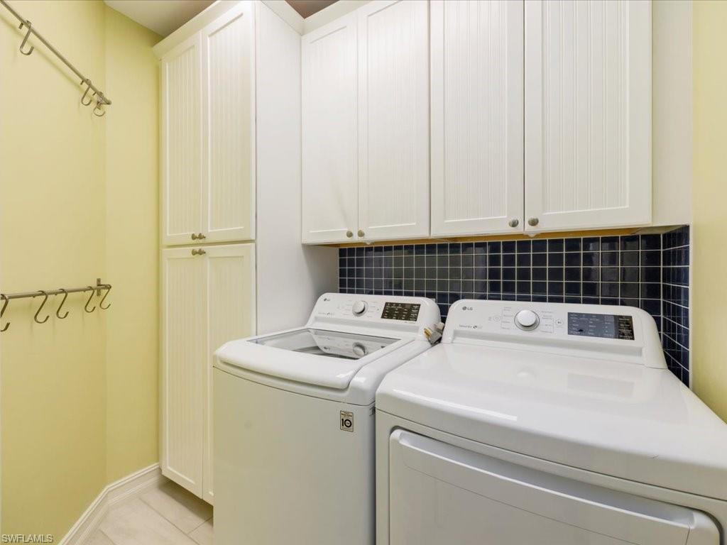 Laundry room with cabinet space, light tile patterned floors, and washing machine and clothes dryer