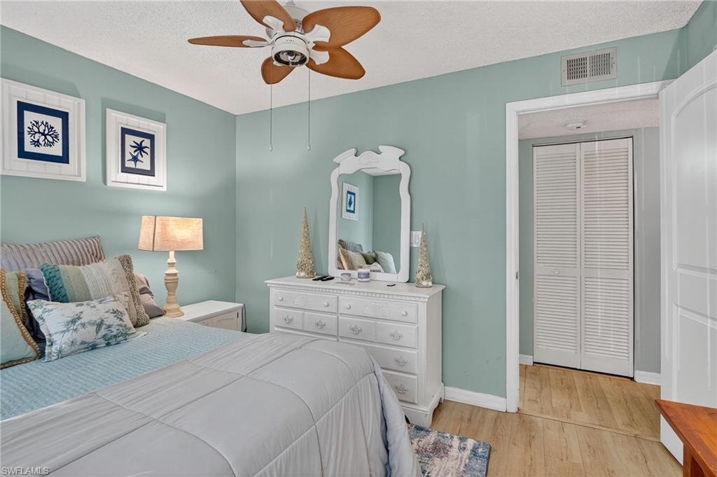 Bedroom with light wood-type flooring, a textured ceiling, and a ceiling fan