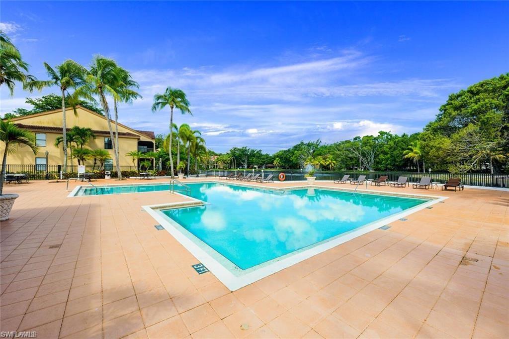 Community pool with a patio area and view of scattered trees