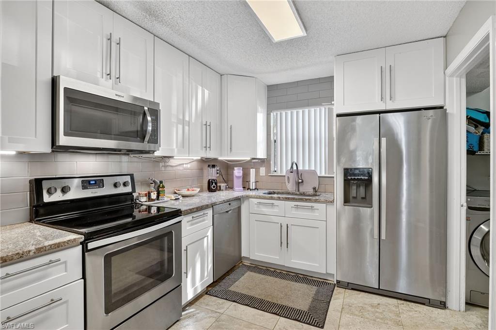 Kitchen with appliances with stainless steel finishes, white cabinetry, and a textured ceiling