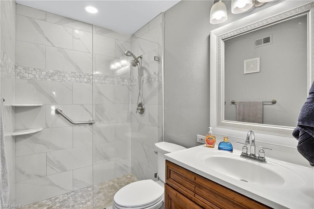 Bathroom with vanity, a stall shower, and a textured wall