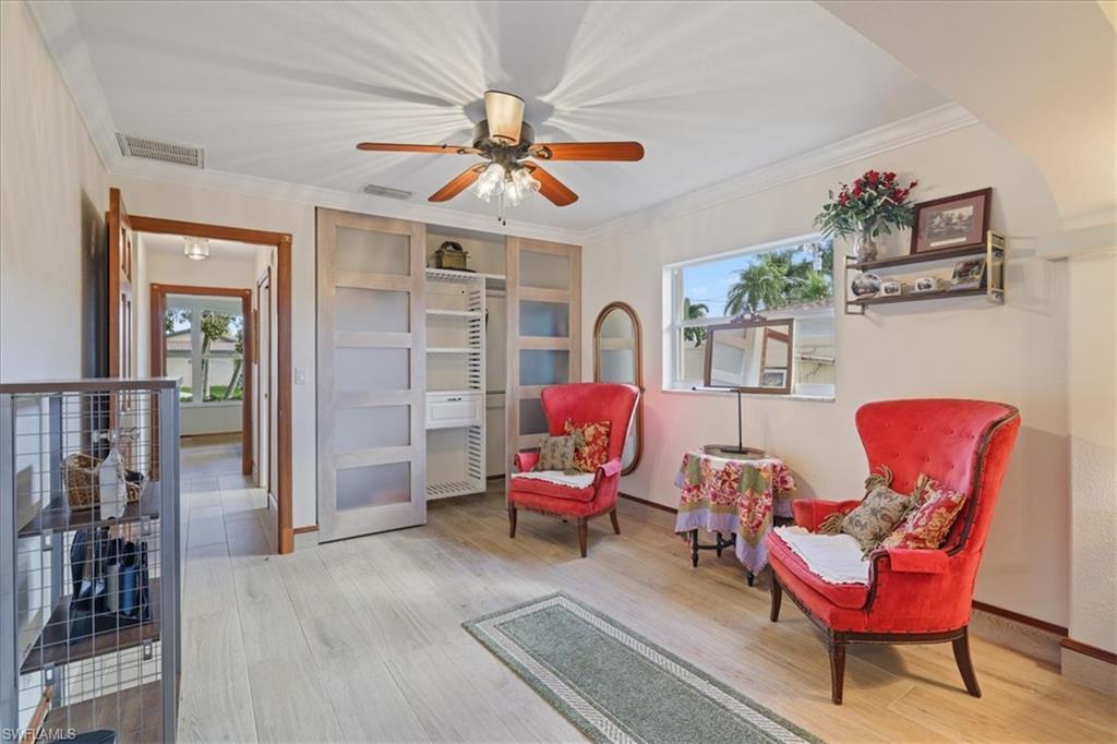 Living area with light wood finished floors, crown molding, and ceiling fan