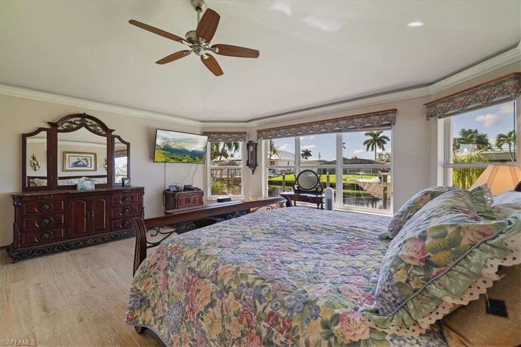 Bedroom featuring crown molding, light wood-style floors, and a ceiling fan