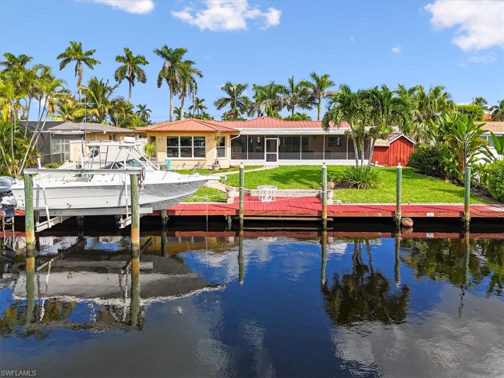 Dock area featuring boat lift, a sunroom, a water view, and a lawn