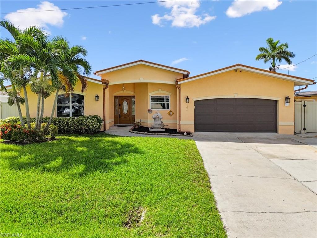 Florida-style house featuring stucco siding, driveway, a garage, and a front lawn