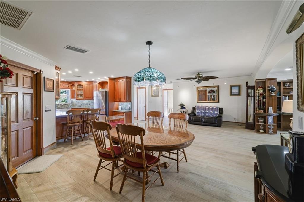 Dining space with light wood-style floors, crown molding, ceiling fan, recessed lighting, and a wood stove