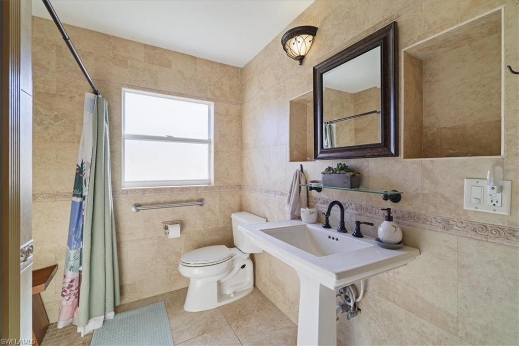 Full bathroom with tile walls, light tile patterned floors, and tiled shower
