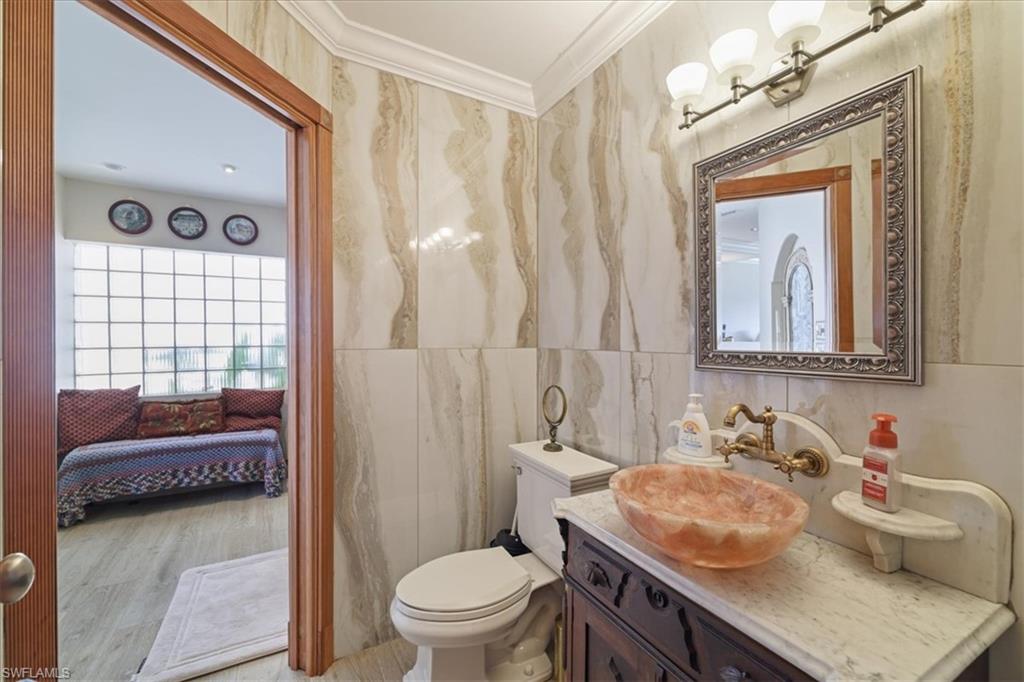 Bathroom with vanity, connected bathroom, tile walls, crown molding, and wood finished floors