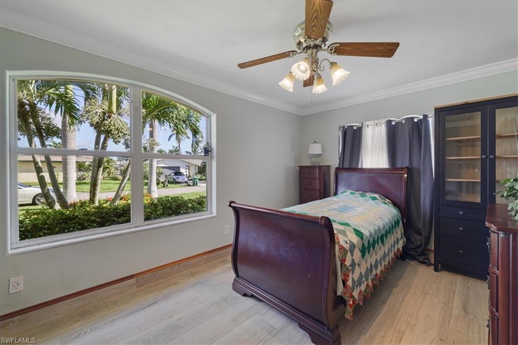 Bedroom featuring ornamental molding, light wood-type flooring, and a ceiling fan