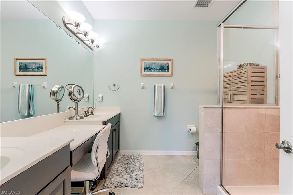 Bathroom with a shower stall, double vanity, and light tile patterned floors
