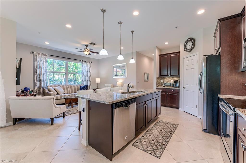 Kitchen with pendant lighting, appliances with stainless steel finishes, open floor plan, ceiling fan, and a kitchen island with sink