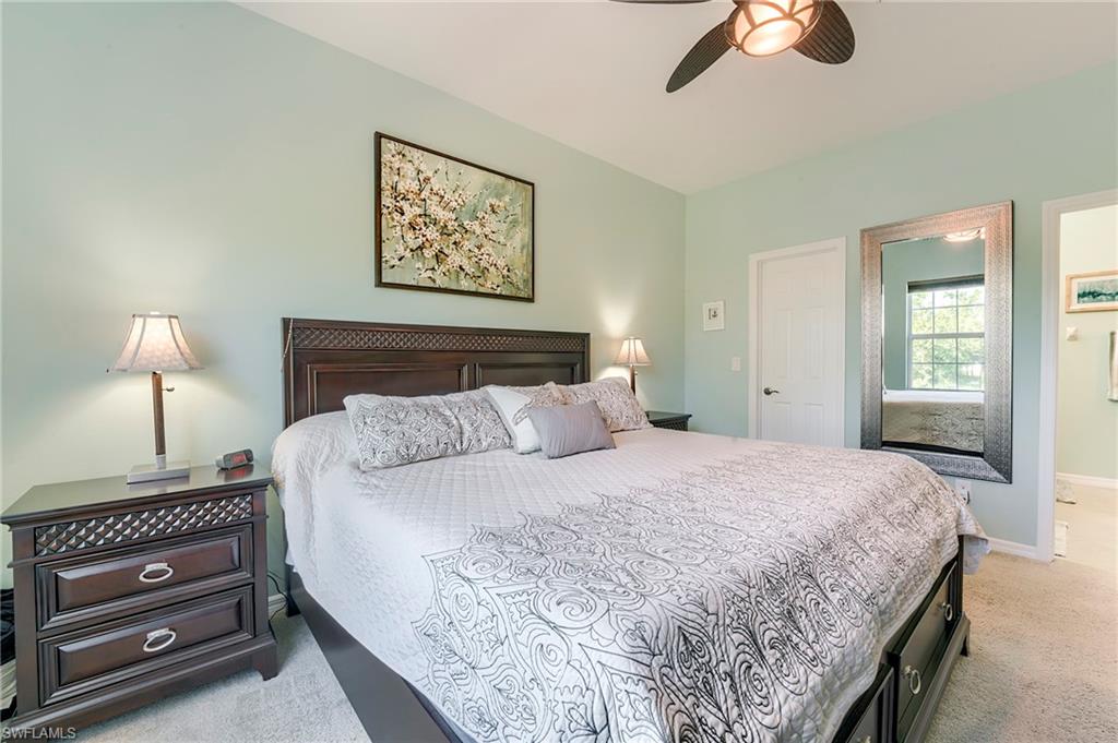 Bedroom with light carpet, a ceiling fan, and ensuite bathroom