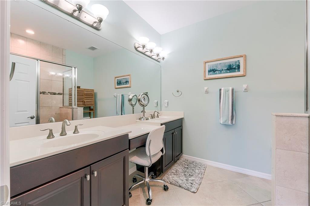 Bathroom featuring a shower stall, double vanity, and light tile patterned floors