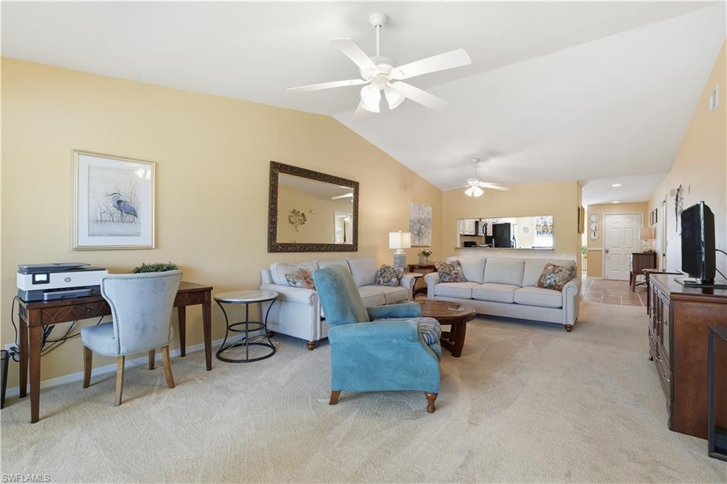 Living area with vaulted ceiling, light colored carpet, and a ceiling fan