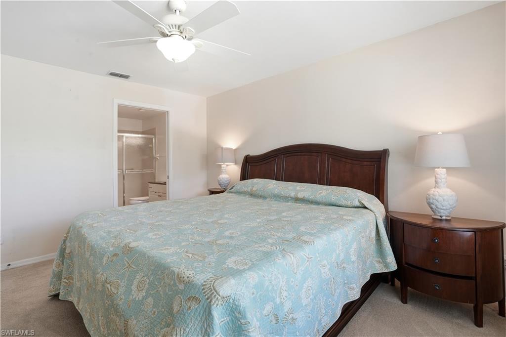 Bedroom with light carpet, ceiling fan, and ensuite bath