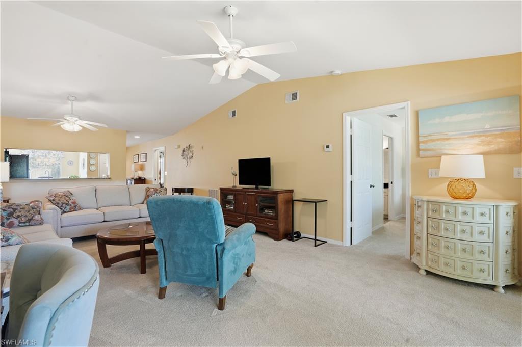 Living room with light carpet, lofted ceiling, and ceiling fan