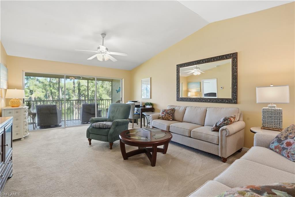 Living area featuring lofted ceiling, light carpet, and a ceiling fan
