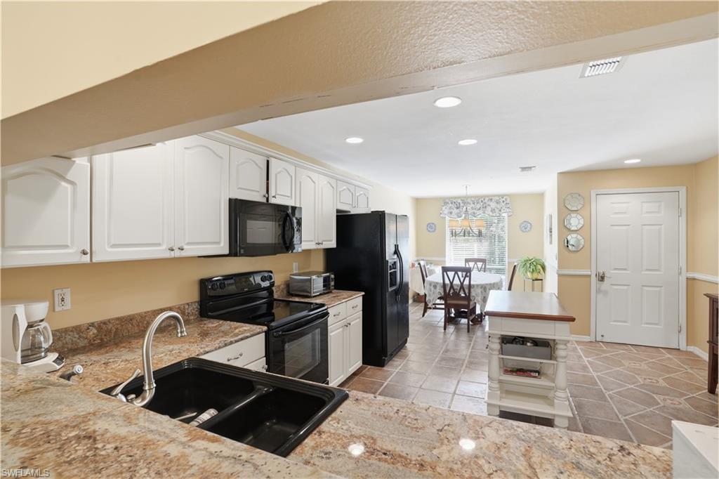 Kitchen featuring black appliances, white cabinetry, recessed lighting, light stone countertops, and light tile patterned floors