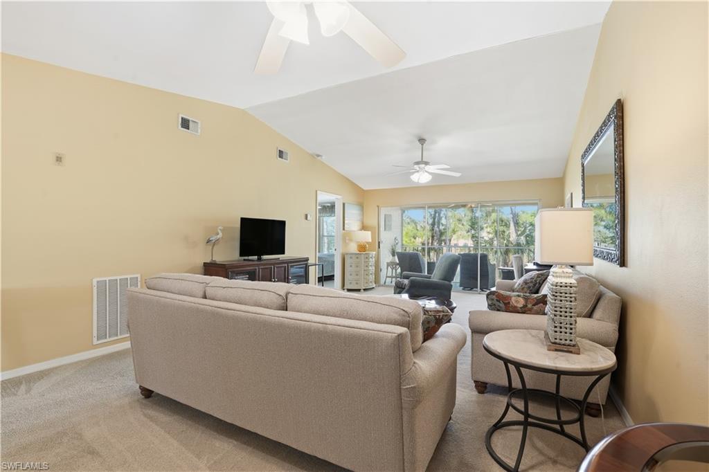 Living area featuring light colored carpet, lofted ceiling, and a ceiling fan