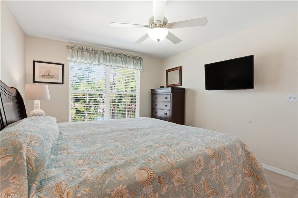 Carpeted bedroom with ceiling fan and baseboards