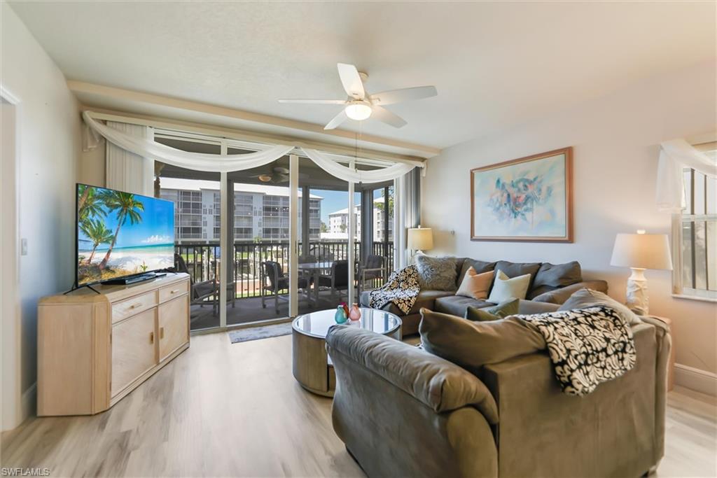 Living room with expansive windows, ceiling fan, and light wood-type flooring