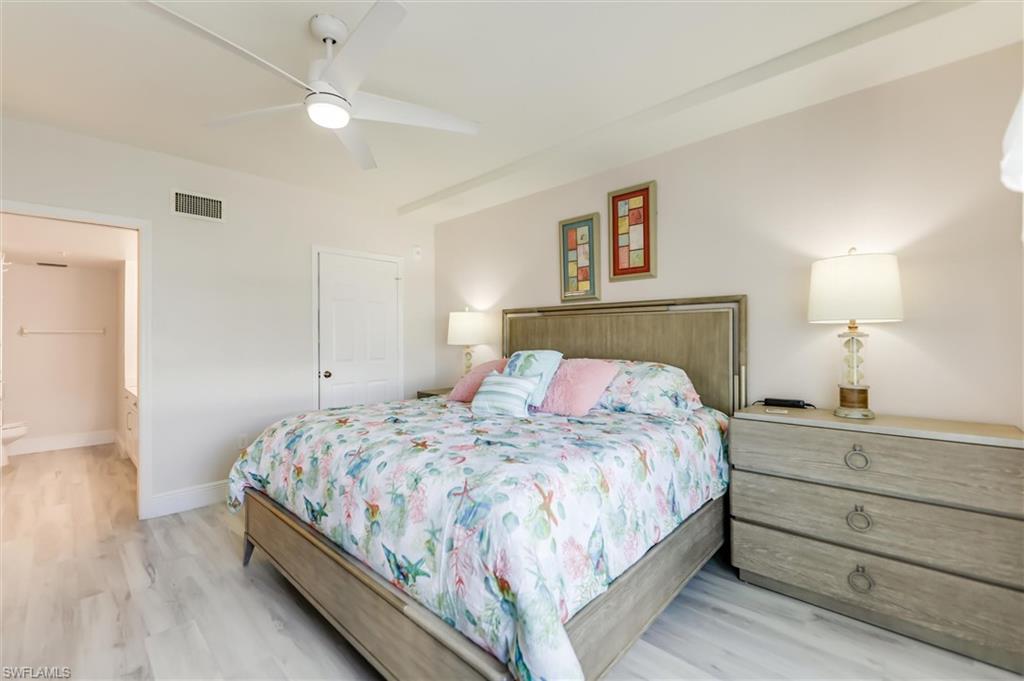 Bedroom with light wood-style floors, ceiling fan, and connected bathroom