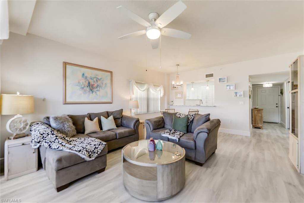 Living room with wood finished floors, ceiling fan, and a chandelier