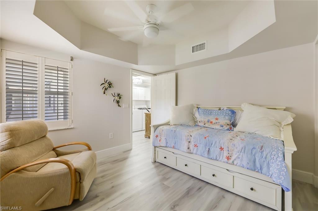 Bedroom featuring a tray ceiling, wood finished floors, and a ceiling fan