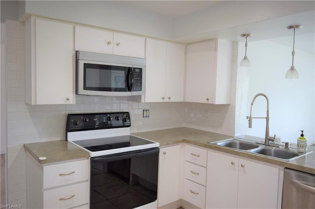 Kitchen with black appliances, white cabinetry, and decorative backsplash