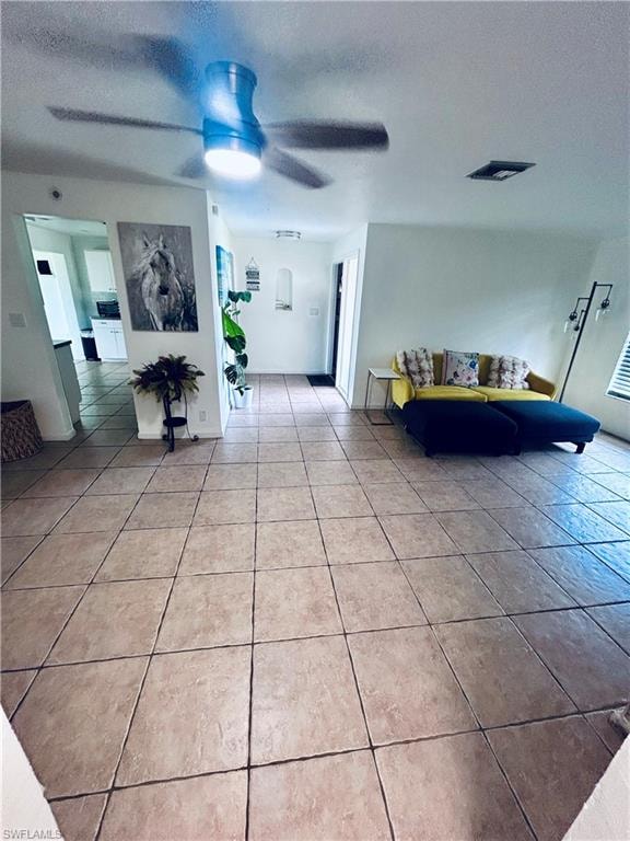 Living area featuring a textured ceiling, light tile patterned floors, and a ceiling fan