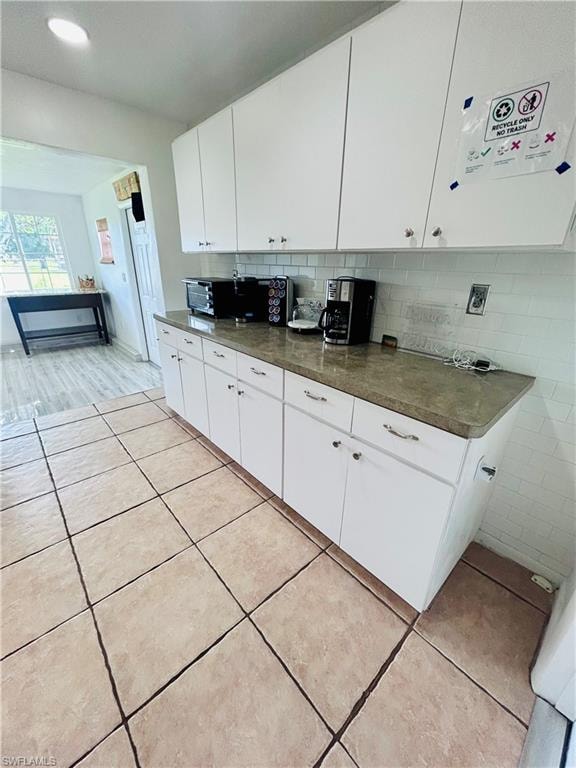 Kitchen featuring white cabinets, decorative backsplash, light tile patterned flooring, and recessed lighting