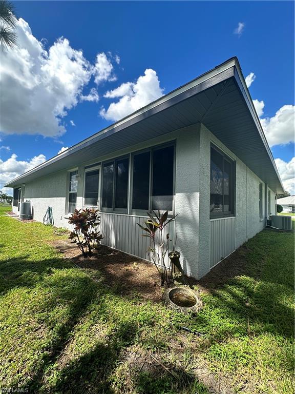 View of home's exterior with a lawn, stucco siding, and a sunroom