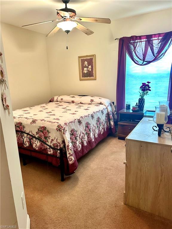 Bedroom with light colored carpet and a ceiling fan