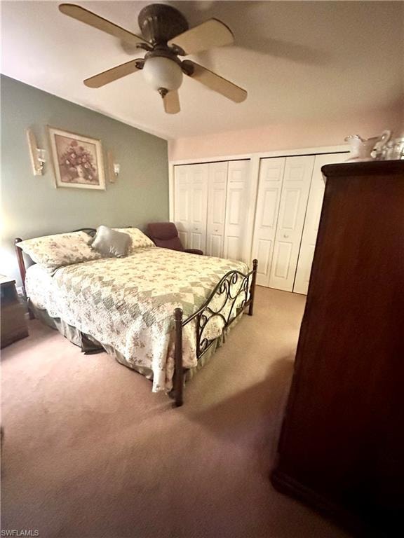 Carpeted bedroom featuring multiple closets and a ceiling fan
