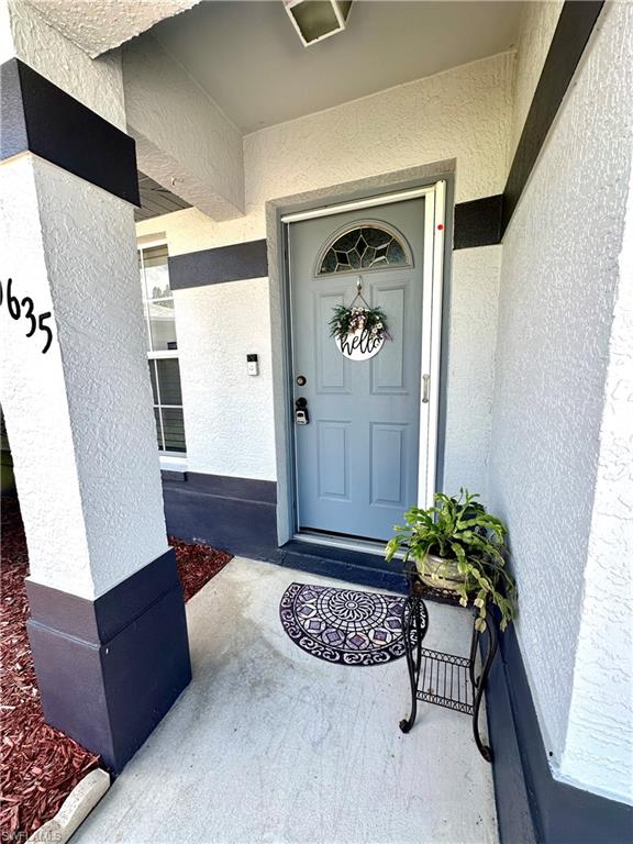 View of exterior entry with stucco siding and a porch