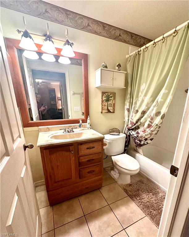 Bathroom featuring shower / bathtub combination with curtain, vanity, and light tile patterned floors