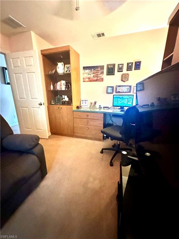 Office space featuring light carpet and built in study area