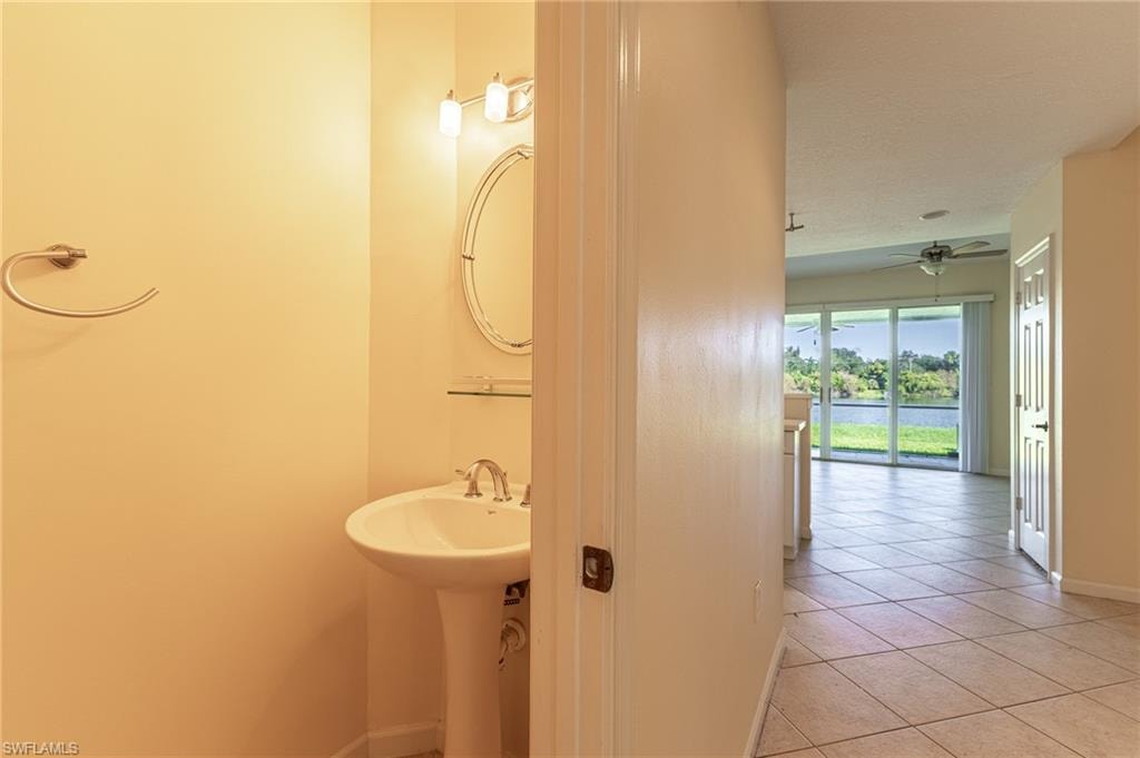 Bathroom with light tile patterned floors, a water view, ceiling fan, and a textured ceiling