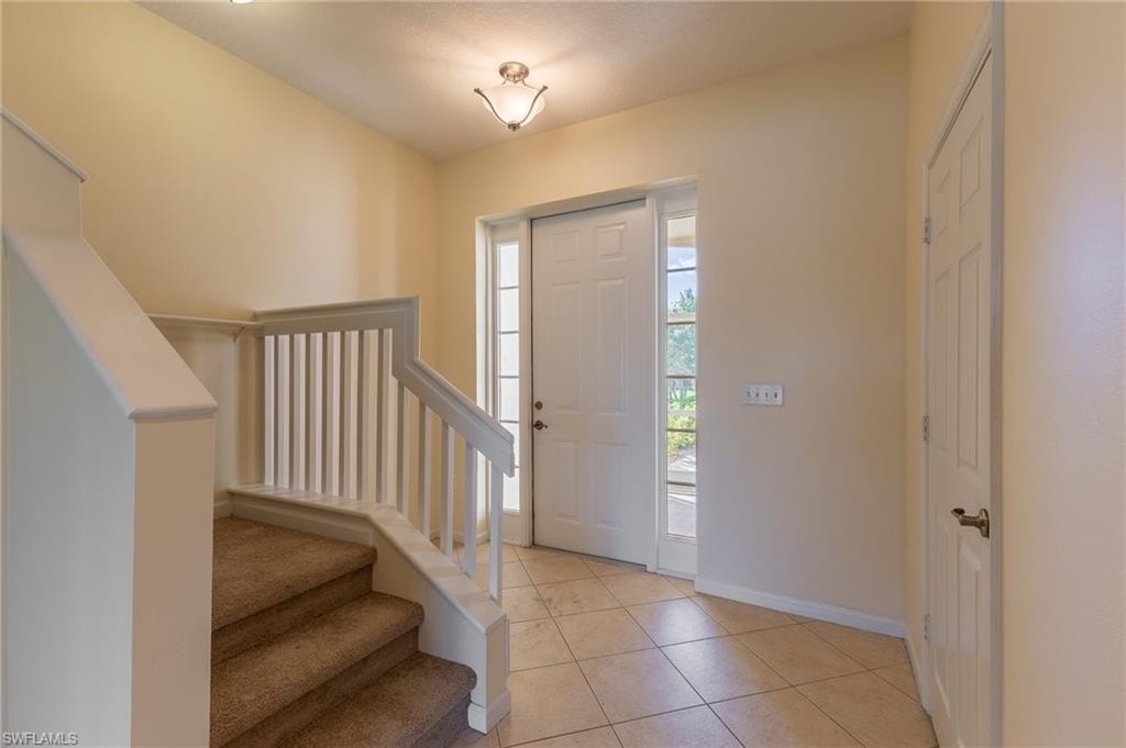 Entrance foyer featuring stairway and light tile patterned floors