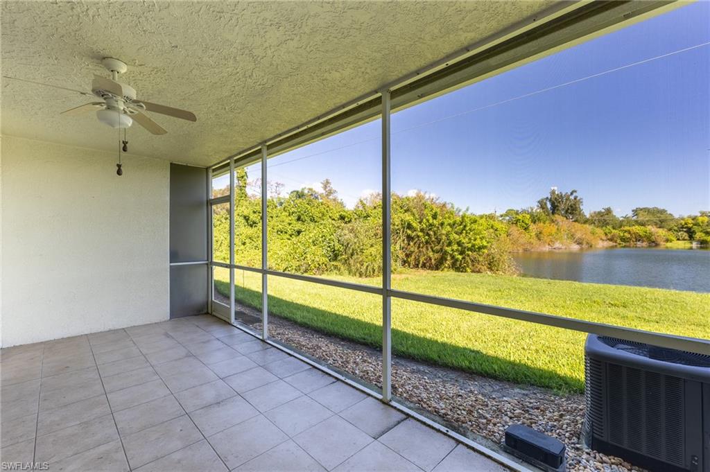 Unfurnished sunroom featuring ceiling fan, a water view, and view of wooded area