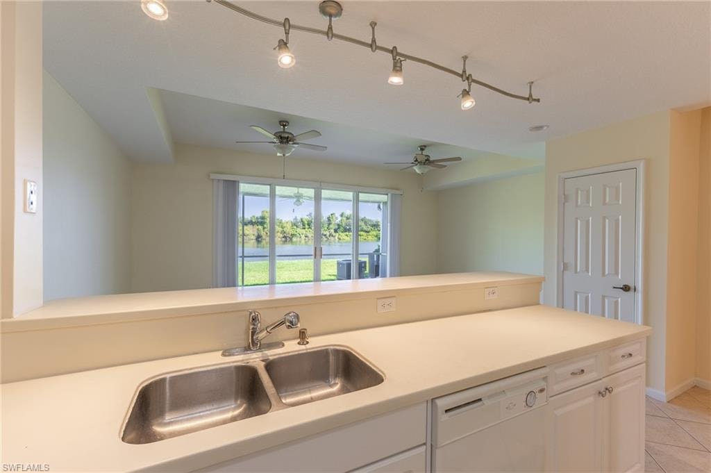 Kitchen featuring white cabinets, light countertops, dishwasher, light tile patterned floors, and track lighting