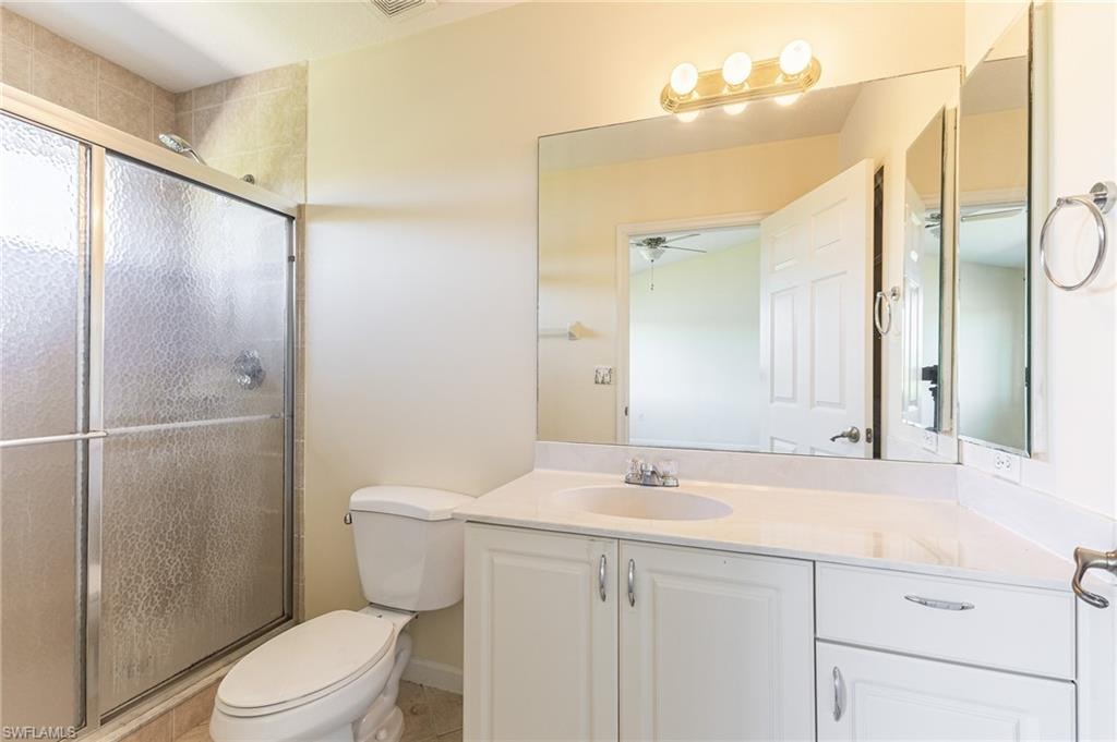 Full bathroom featuring vanity, a shower stall, light tile patterned flooring, and a ceiling fan