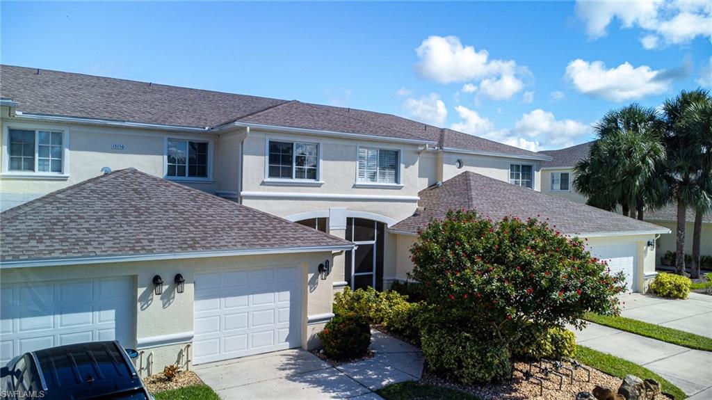 Traditional-style house with stucco siding, a garage, a shingled roof, and concrete driveway