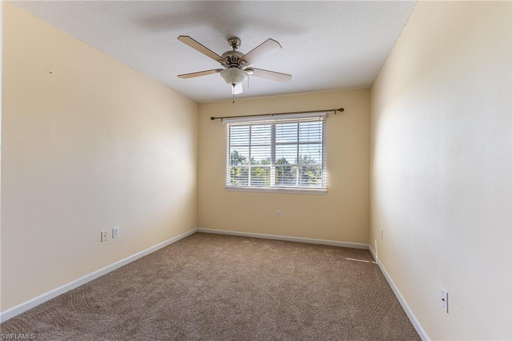 Carpeted empty room with baseboards and ceiling fan